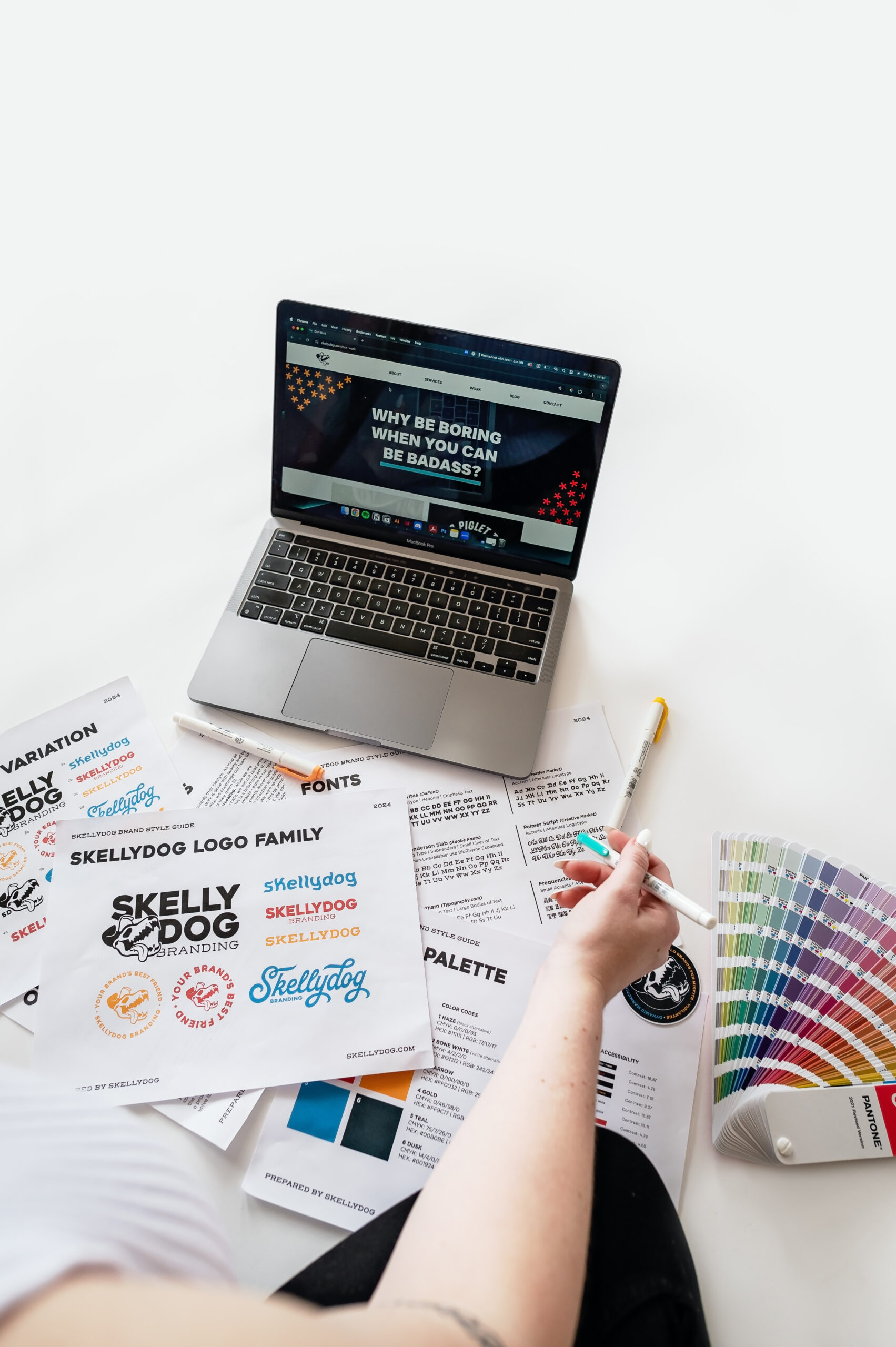 laptop laying on ground with paper and color swatches around laptop. website on laptop open to portfolio page
